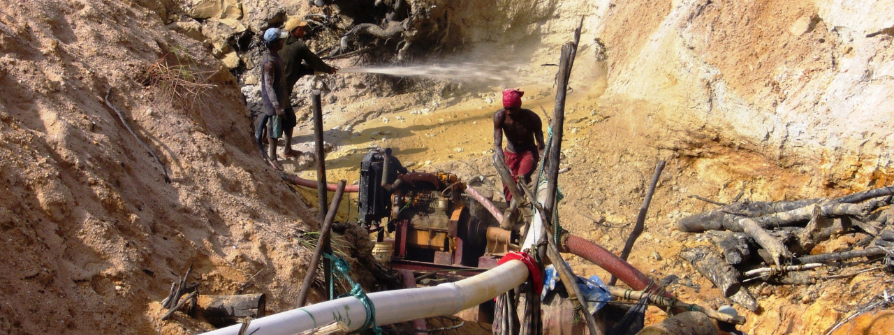 Arbeiter*innen im Amazonasgebiet von Guayana pumpen goldhaltigen Schlamm aus einsturzgefährdeten, staubigen Minengruben
