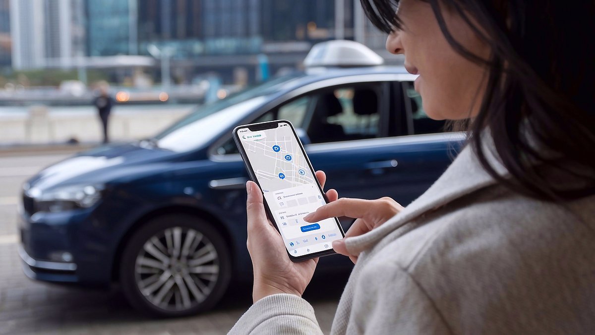 Frau betrachtet ihr Handy mit Car-Sharing Stationen