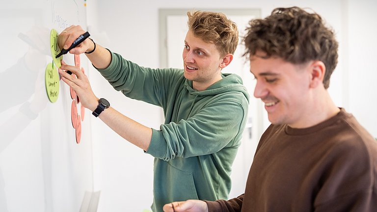 Zwei Männer arbeiten an einer Tafel und sammeln Ideen.