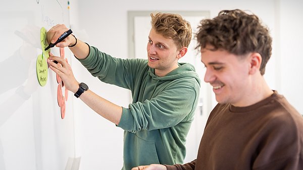 Zwei Männer arbeiten an einer Tafel und sammeln Ideen.