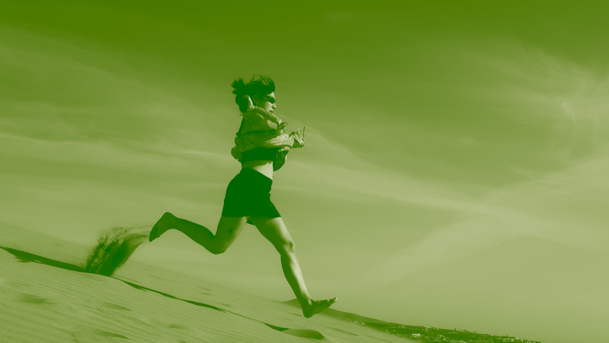 Seitenaufnahme einer jungen Frau, die einen Berg runterläuft. 