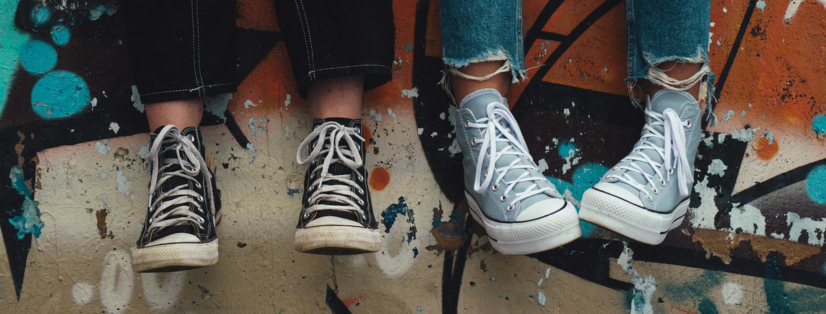 Zwei Jugendliche sitzen auf einer Anhöhe und lassen die Füße baumeln