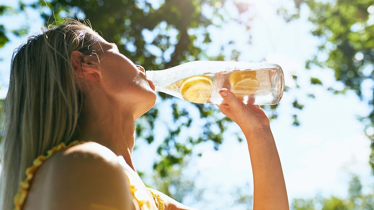 Eine Frau trinkt Zitronenwasser im Freien
