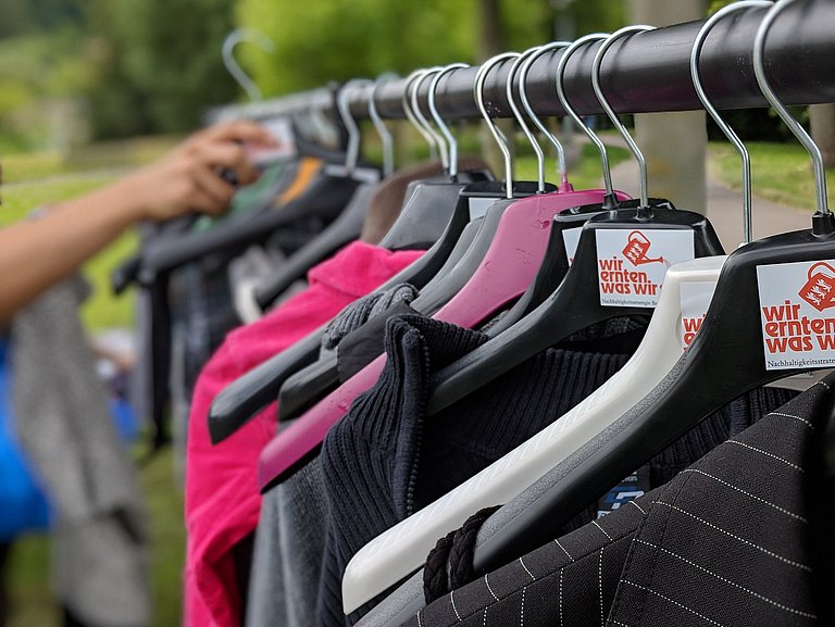 Kleider hängen auf einer Stange mit Logo von WEWWS
