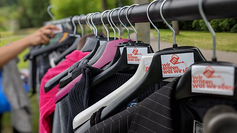 Kleider hängen auf einer Stange mit Logo von WEWWS