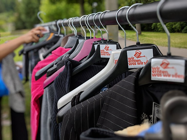 Kleider hängen auf einer Stange mit Logo von WEWWS