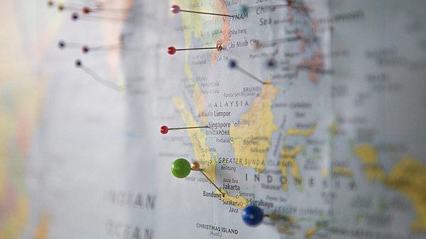 Stecknadeln markieren verschiedenen Ländern auf einer Weltkarte
