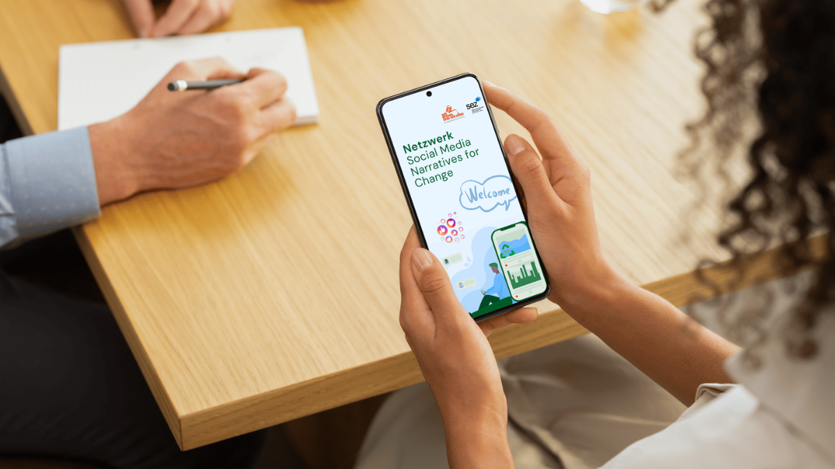 Frau hält Smartphone in der Hand, auf Bildschirm ist das Titelbild des Social Media Netzwerks zu sehen