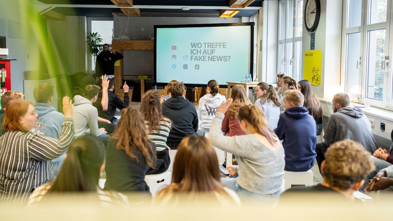 Junge Menschen hören einem Vortrag zu. 