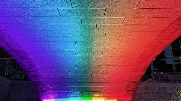 Farbiges Licht beleuchtet den Bereich unter einer Brücke