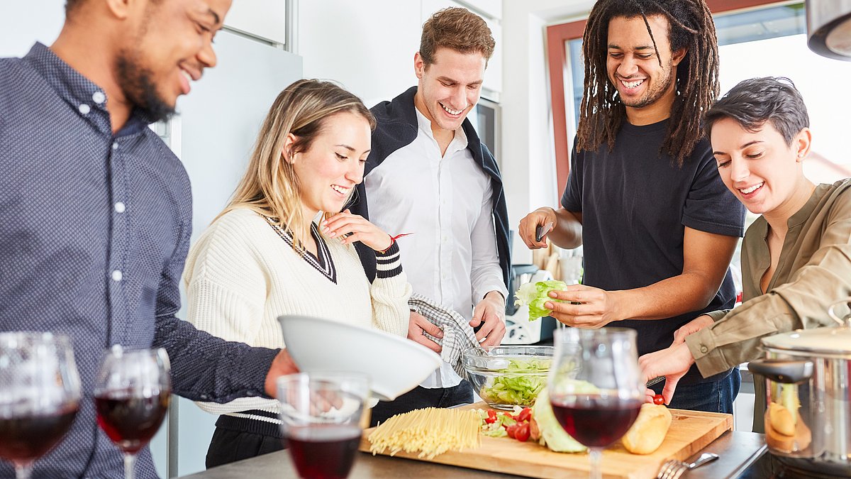 Ein diverse Gruppe junger Menschen kocht gemeinsam