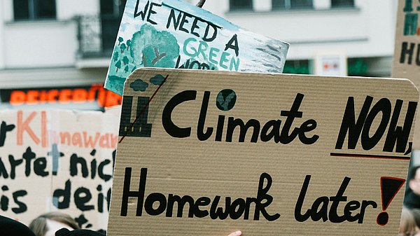 Menschen auf einer Klimademo mit Schild "climate now, homework later"