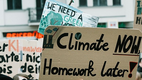 Menschen auf einer Klimademo mit Schild "climate now, homework later"