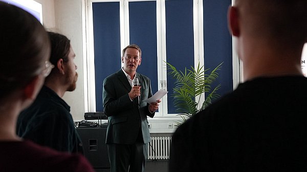 Jugend- und Sozialminister Oliver Hildenbrand spricht zu jungen Menschen und Landtagsabgeordneten
