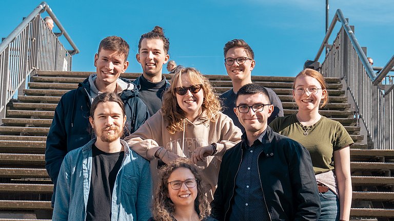 Gemischte Gruppe junger Menschen aus dem Jugendrat stehen auf einer Treppe und lachen