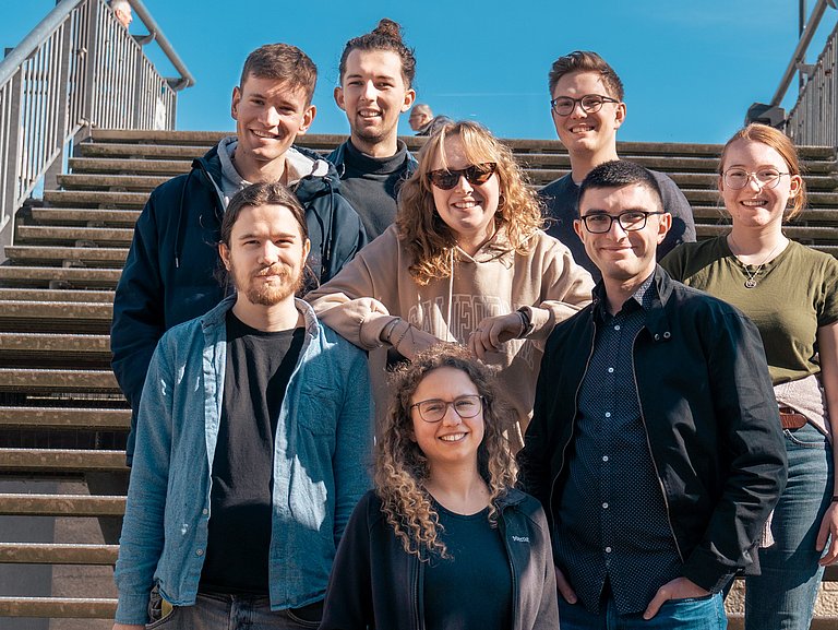 Gemischte Gruppe junger Menschen aus dem Jugendrat stehen auf einer Treppe und lachen