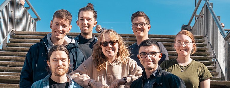 Gemischte Gruppe junger Menschen aus dem Jugendrat stehen auf einer Treppe und lachen