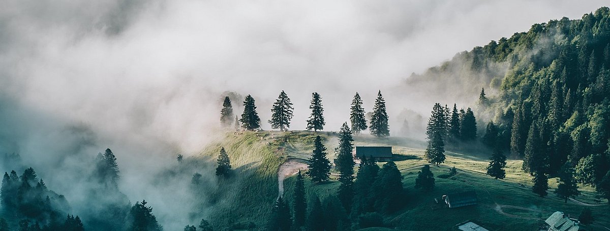 Stimmungsvolles Foto einer Alpenlandschaft mit Sonne und Neben