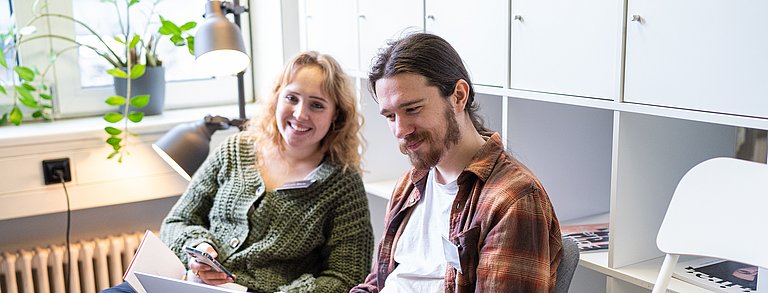 Zwei junge Erwachsene arbeiten an einem Laptop.