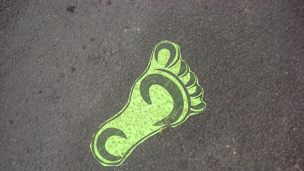 Grafik eines grünen Fußabdrucks auf Asphalt
