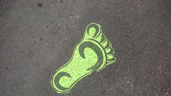 Grafik eines grünen Fußabdrucks auf Asphalt