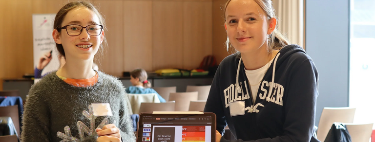 Zwei Umweltmentorinnen zeigen beim Projektmarkt 2023 Ergebnisse.