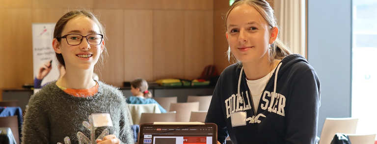 Zwei Umweltmentorinnen zeigen beim Projektmarkt 2023 Ergebnisse.