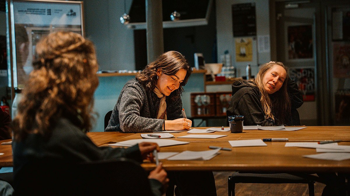 Drei Frauen sitzen an einem Tisch und tauschen sich aus