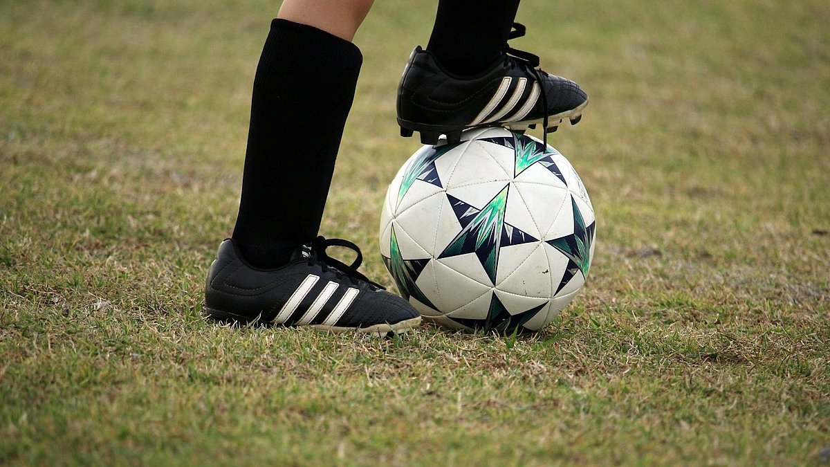 Ein Spieler hat den Fußball zwischen den Beinen