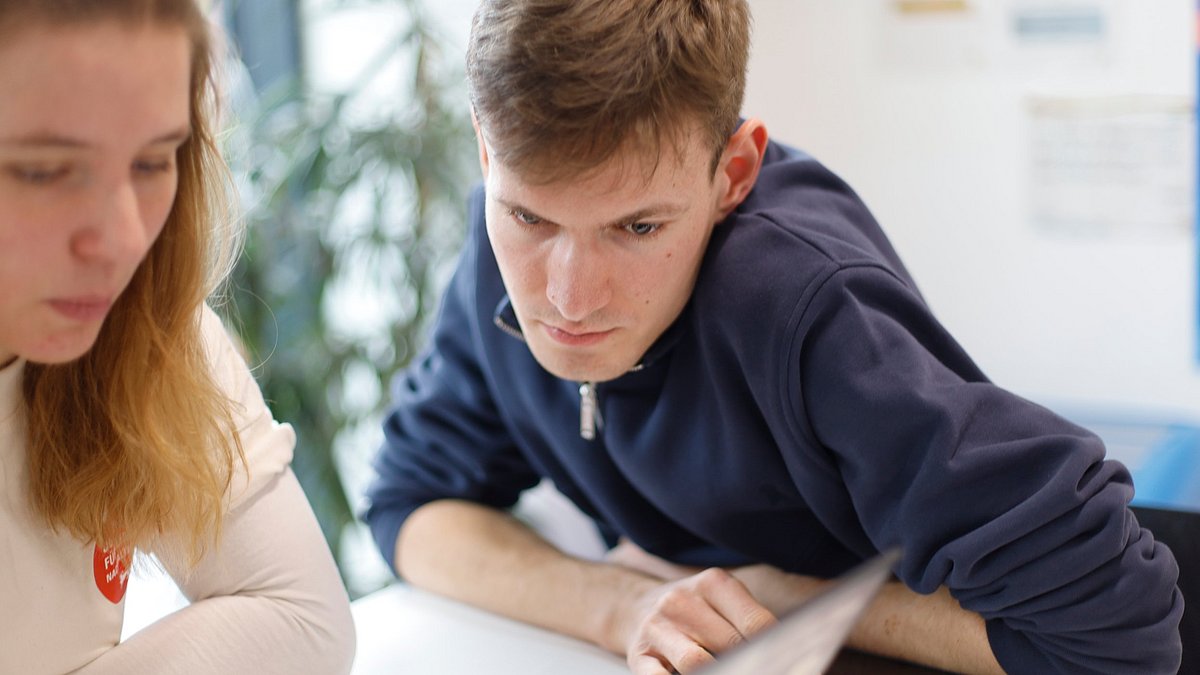Jugendlicher schaut auf Laptop einer zweiten Person