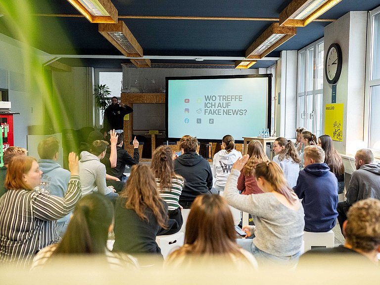 Junge Menschen hören einem Vortrag zu. 