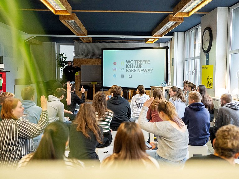 Junge Menschen hören einem Vortrag zu. 