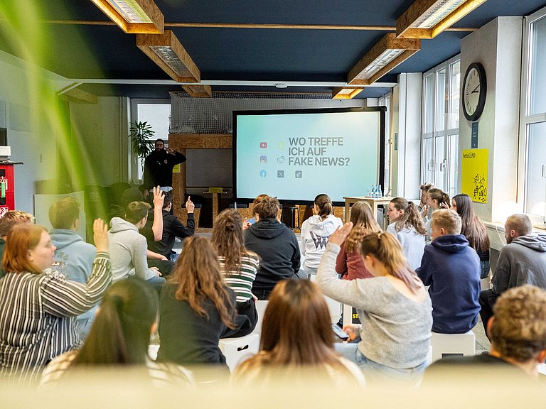 Junge Menschen hören einem Vortrag zu. 