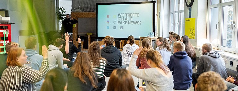 Junge Menschen hören einem Vortrag zu. 