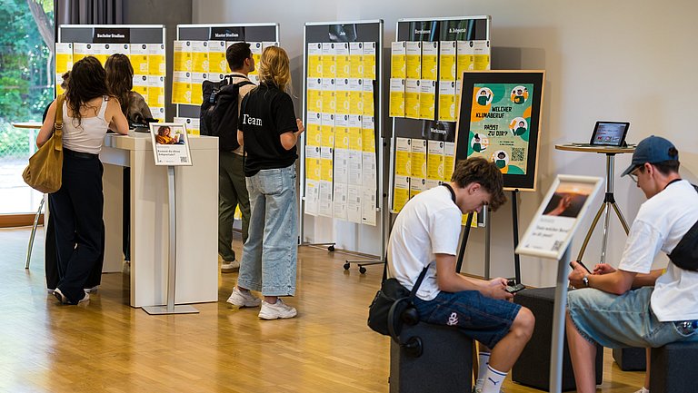 Junge Menschen stehen vor Pinnwänden und informieren sich 