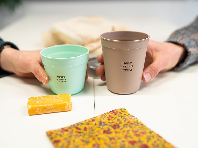 Hände halten widerverwendbare Kaffebecher. 