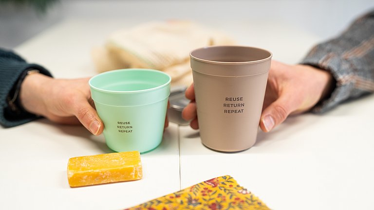 Hände halten widerverwendbare Kaffebecher. 