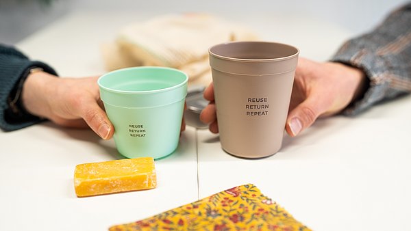 Hände halten widerverwendbare Kaffebecher.