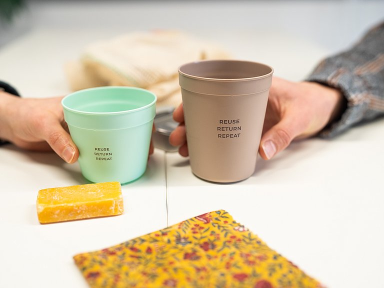 Hände halten widerverwendbare Kaffebecher. 