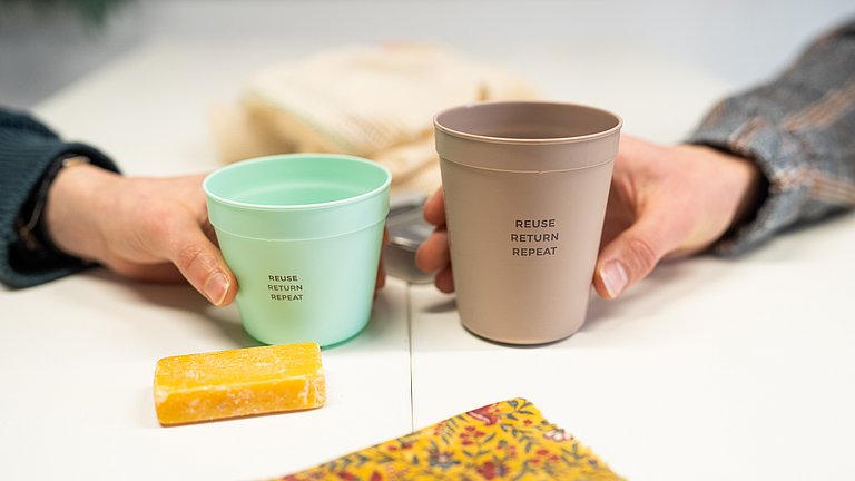 Hände halten widerverwendbare Kaffebecher. 