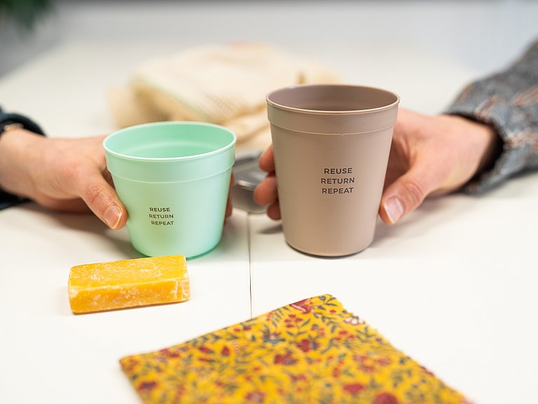 Hände halten widerverwendbare Kaffebecher. 