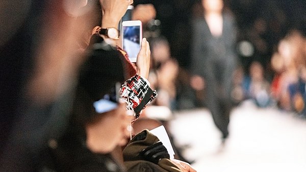 Zuschauer halten Handys gezückt an einem Laufsteg