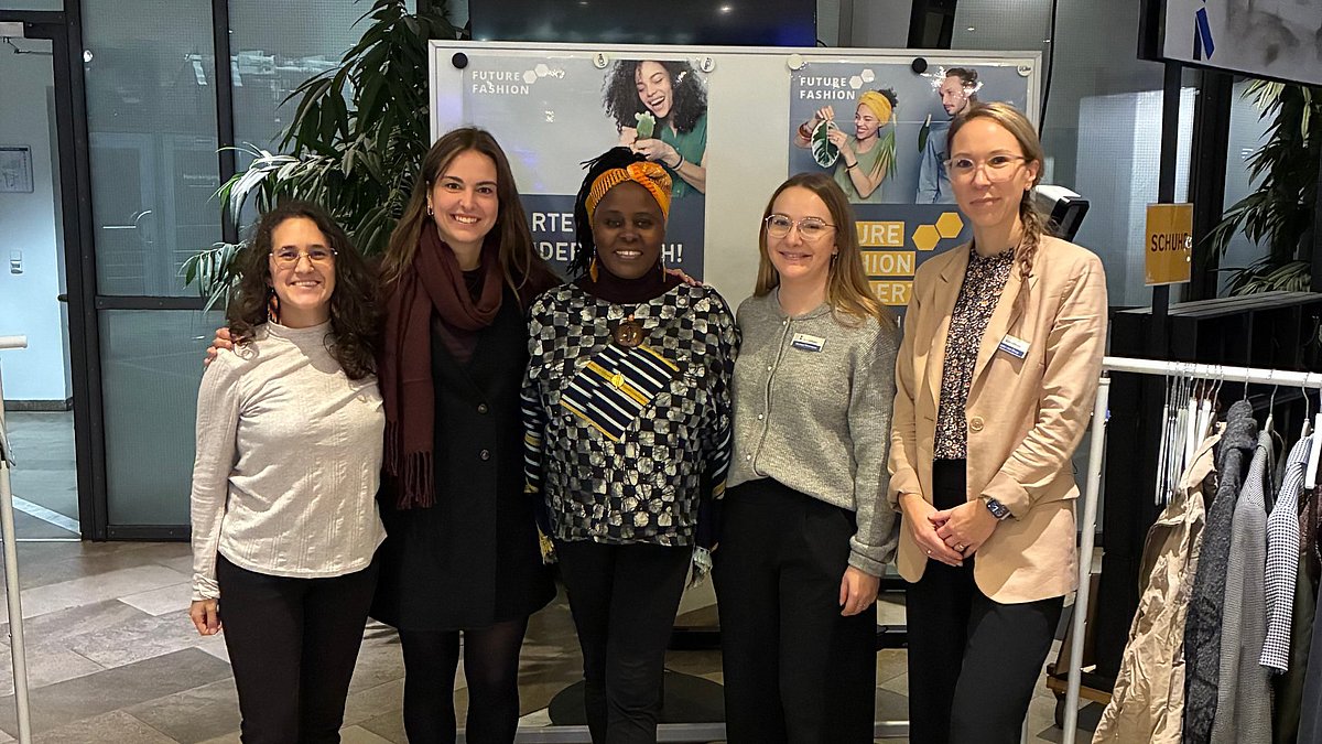 Mehrere Frauen stehen gemeinsam vor Kleiderstangen auf einer Kleidertauschparty