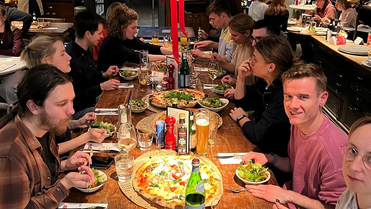 Eine Gruppe sitzt beim Pizza essen zusammen