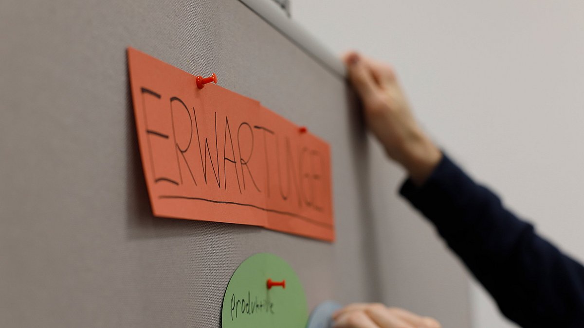 An eine Pinnwand gepinntes Kärtchen mit der Aufschrift „Erwartungen“