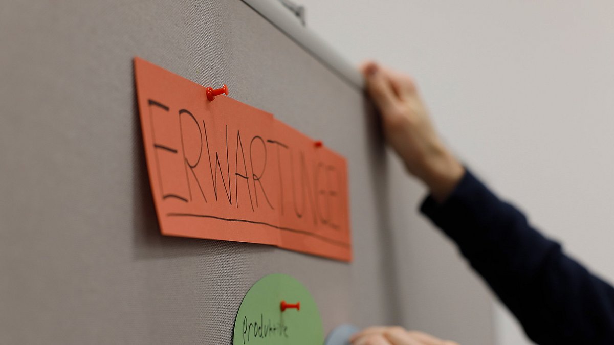 Ein Kärtchen mit der Aufschrift "Erwartungen" wurde an eine Pinnwand gepinnt