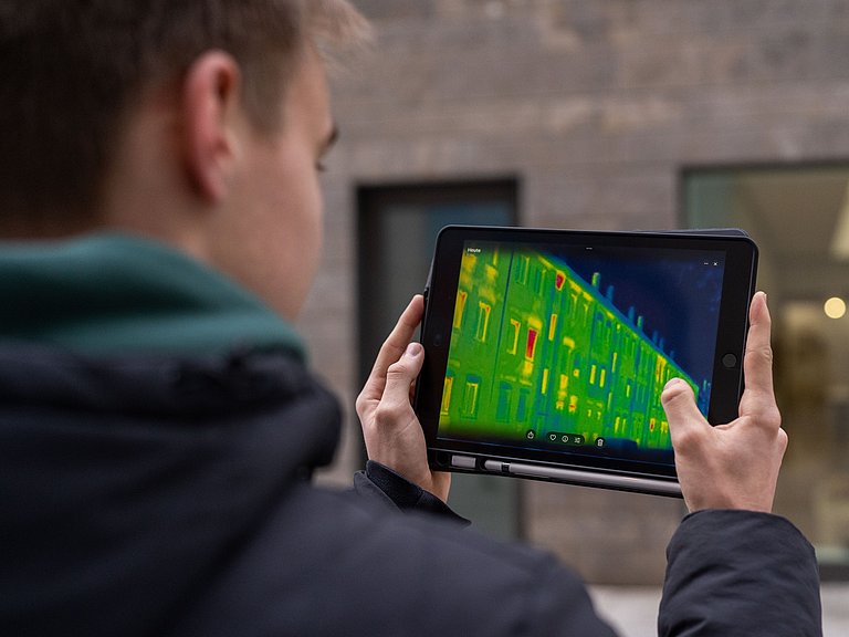 Junger Mann hält ein Tablet mit einer Wärmebildkamera