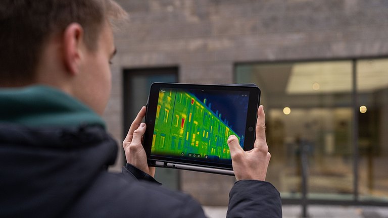 Junger Mann hält ein Tablet mit einer Wärmebildkamera
