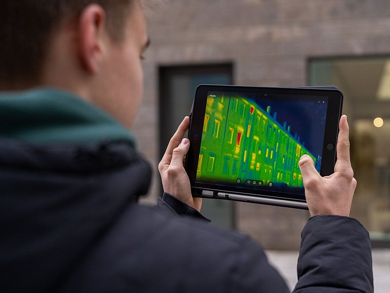 Junger Mann hält ein Tablet mit einer Wärmebildkamera
