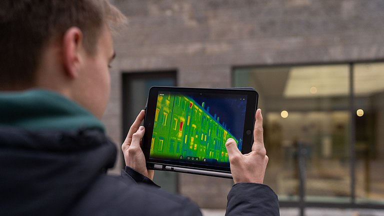Junger Mann hält ein Tablet mit einer Wärmebildkamera